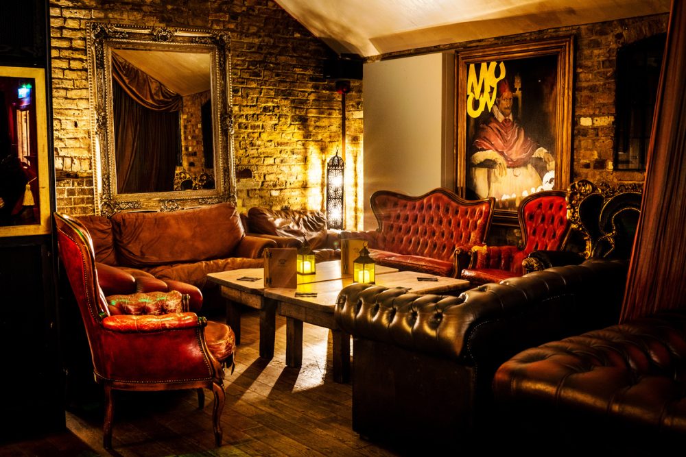 Elegant Hoochie Coochie Lounge featuring plush leather seating, vintage furnishings, and soft lighting, ideal for hosting events and gatherings.